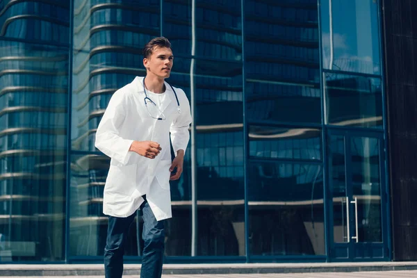 doctor with a stethoscope runs quickly along a city street.