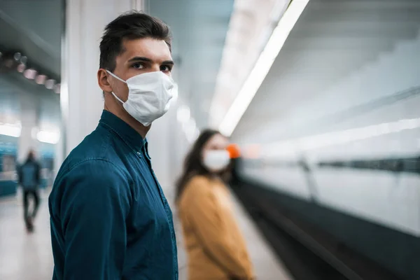 Passagers portant des masques de protection debout à une station de métro à une distance sûre — Photo