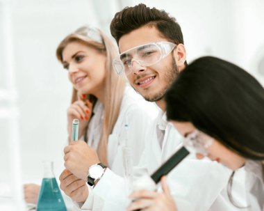 Yakın plan. Bir grup genç bilim adamı deneyler yapıyor.