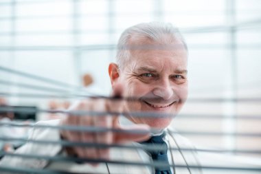 Gülümseyen başarılı iş adamı perdelerden bakıyor..