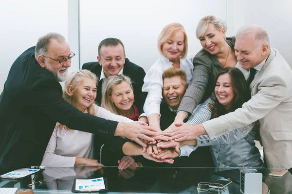 Grupo de empleados que se unen a sus palmas sobre el escritorio. — Foto de Stock