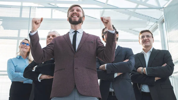 Close up. happy businessman standing in front of his team — Stock Photo, Image