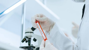 Kapat. Laboratuvar çalışanı laboratuvar masasında oturuyor.