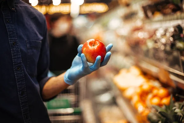 Fresh Apple in the hands of a man in protective gloves — Stock Photo, Image