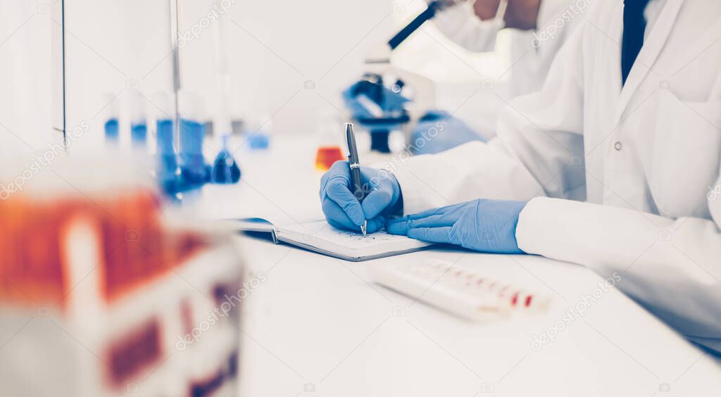 close up. scientist recording the results of the study in a laboratory journal.