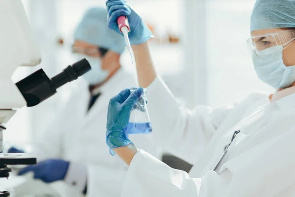 Fecha. cientista fêmea examinando um líquido em um frasco de laboratório . — Fotografia de Stock