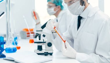 Kapat. Bilim adamı yeni bir test numunesi içeren bir tüp tutuyor..