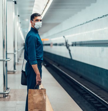 Korumalı maskeli yolcular metro trenini bekliyor.