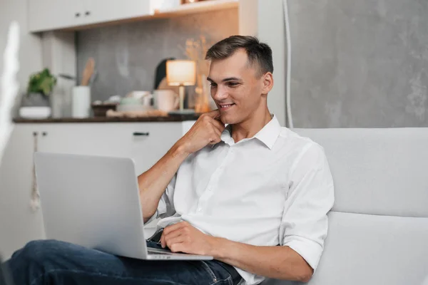 Usmívající se mladý muž se dívá na obrazovku svého notebooku . — Stock fotografie