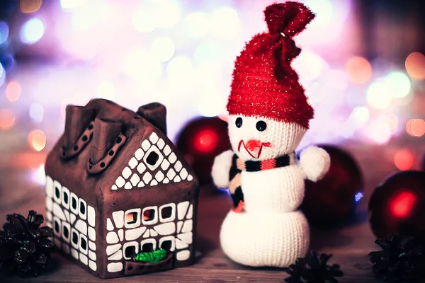 Speelgoed sneeuwpop en peperkoek huis aan de kersttafel — Stockfoto