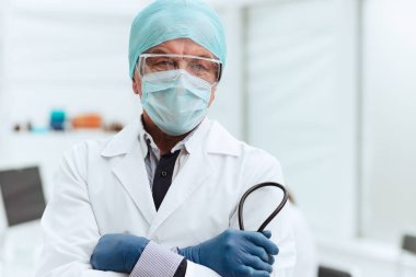 Kapat. Laboratuvarda duran koruyucu maskeli bir doktor..