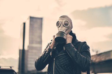 Şehir caddesinde gaz maskesi takan genç bir adam.