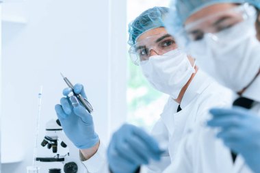 Kapat. Laboratuvarda çalışan koruyucu giysili bir grup bilim adamı..