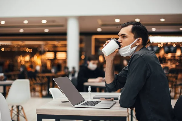 Homme dans un masque de protection assis à une table dans un café — Photo