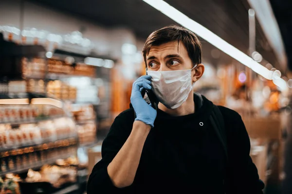 Doe dicht. jonge man met een beschermend masker praten op zijn smartphone. — Stockfoto