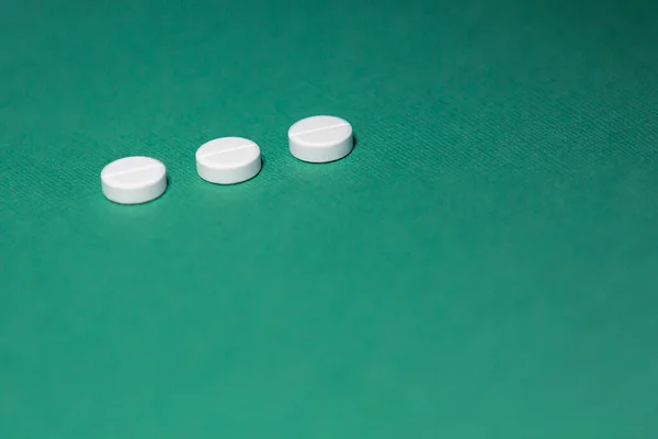 Nahaufnahme. drei Tabletten auf grünem Hintergrund. — Stockfoto