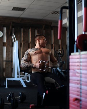 Vücut geliştirici spor salonundaki bir simülatörde egzersiz yapıyor..