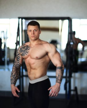 Modern bir spor salonunda poz veren çekici genç bir vücut geliştirici..