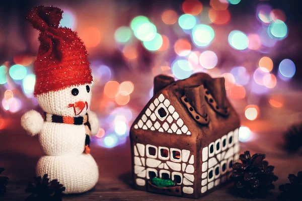 Іграшковий сніговик і пряниковий будинок за різдвяним столом — стокове фото