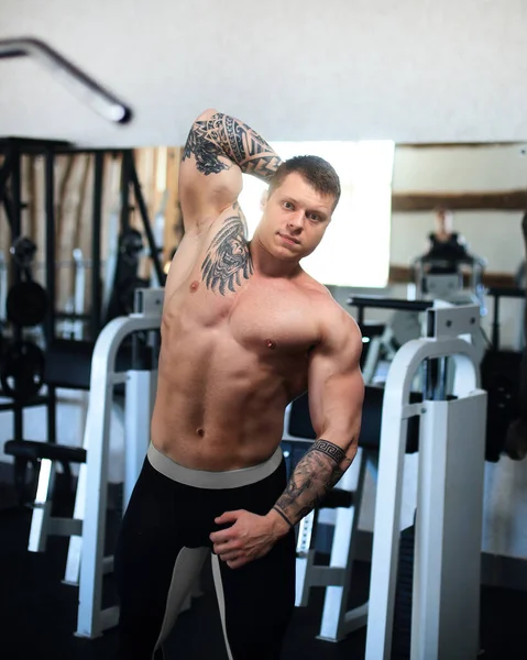 Vista lateral. joven culturista en el gimnasio. — Foto de Stock