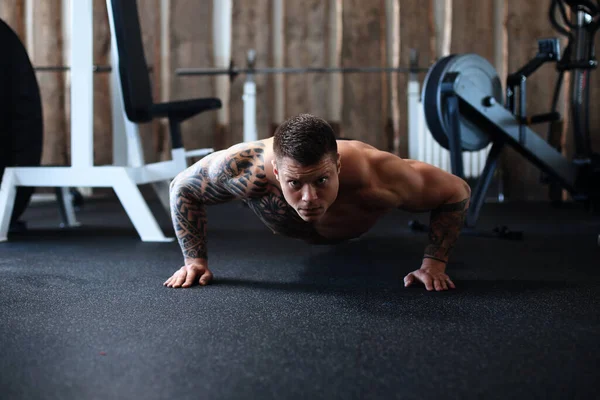 Αφιερωμένο bodybuilder εκτελεί push-UPS στο γυμναστήριο. — Φωτογραφία Αρχείου