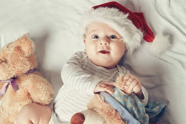 Mutlu bebek Noel Baba şapkası içinde yumuşak oyuncaklarla — Stok fotoğraf