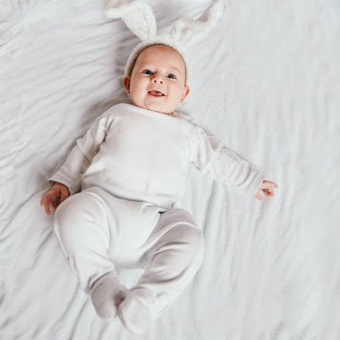 Sevimli, gülümseyen bebek yatakta yatıyor..