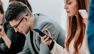 Bir grup farklı genç insan akıllı telefonlarının ekranlarına bakıyor.