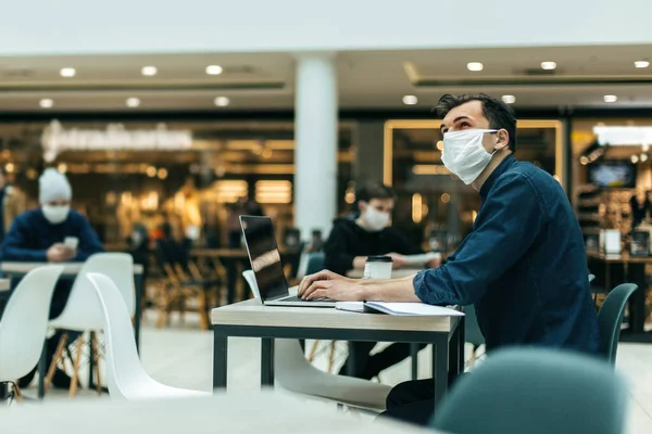 Image de personnes portant des masques de protection utilisant des ordinateurs portables dans une aire de restauration. — Photo