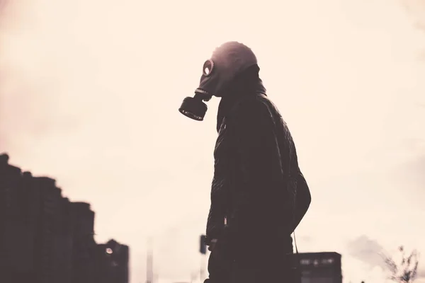 Jovem casual em uma máscara de gás em pé na rua em uma cidade vazia — Fotografia de Stock