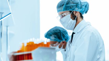 Kapat. Koruyucu giysiler içinde bir grup virüs uzmanı laboratuvarda çalışıyor..