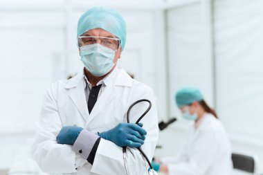 Kapat. Laboratuvarda duran koruyucu maskeli bir doktor..
