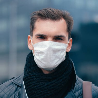 Koruyucu maskeli adam kendinden emin bir şekilde ileriye bakıyor.