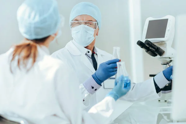 Colegas científicos discutem sentar-se à mesa do laboratório. — Fotografia de Stock