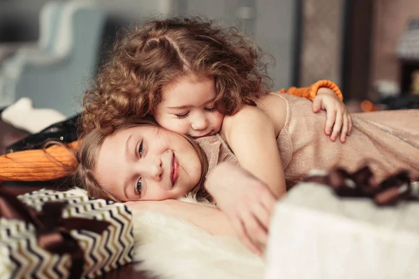 İki güzel kız kardeş sıcak bir oturma odasında eğleniyorlar. — Stok fotoğraf