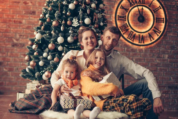 Twee zussen en hun ouders zitten naast de kerstboom — Stockfoto
