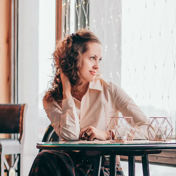 Söt ung kvinna sitter vid ett bord på ett café — Stockfoto