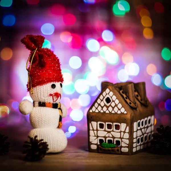 Toy snowman and gingerbread house at the Christmas table — Stock Photo, Image