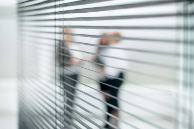 Panjurların arasından. Ofis lobisinde konuşan bir grup iş kadını.