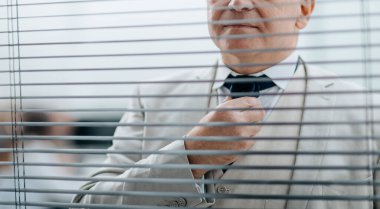 Kapat. Ofis penceresinin önünde duran ciddi bir iş adamı.