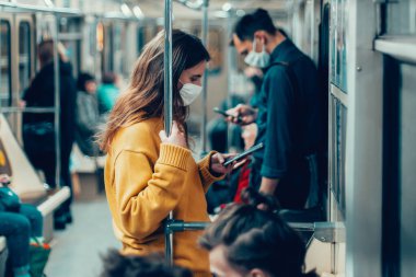 çeşitli yolcular metro vagonuna biniyor.