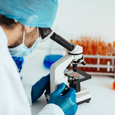 Bilim adamı mikroskopla kontrol örneğine bakıyor..