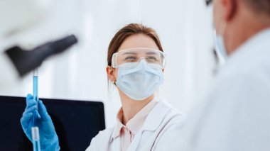 Kapat. Kadın bilim adamı deney tüplerindeki sıvıya bakıyor..