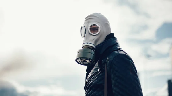 Pemuda santai dalam masker gas berdiri di jalan di kota kosong — Stok Foto