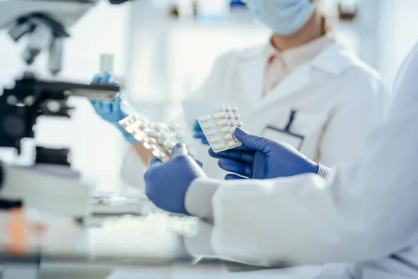 Científicos con muestras de nuevos fármacos sentados en una mesa de laboratorio. —  Fotos de Stock
