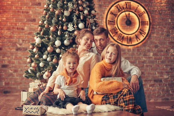 Mutlu aile Noel ağacının yanında oturuyor rahat oturma odasında — Stok fotoğraf
