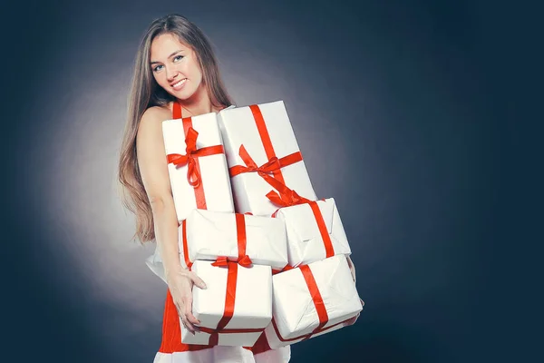 Stylish young woman in costume of Santa Claus with Christmas gif — Stock Photo, Image