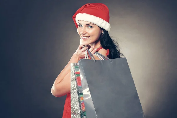 Feliz jovem mulher vestida como Papai Noel com as compras de Natal. — Fotografia de Stock