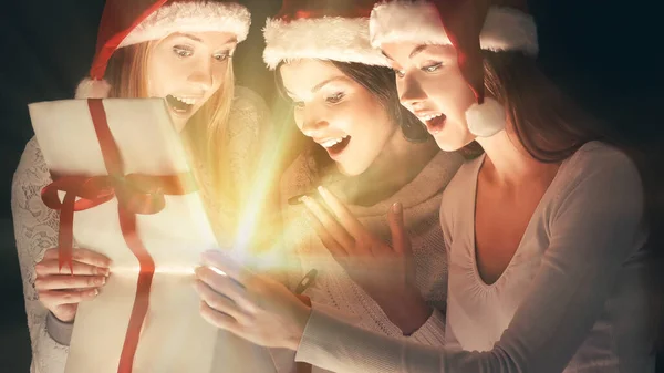 Grupo de estudantes do sexo feminino em trajes de Papai Noel abrindo uma caixa de presentes de Natal . — Fotografia de Stock