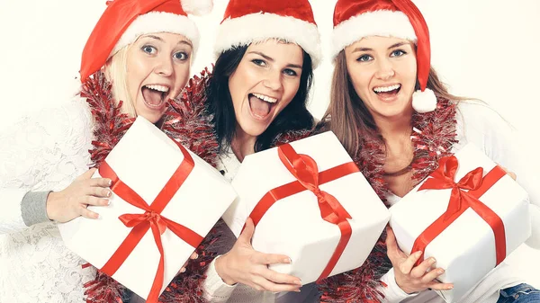 Drei junge Frauen in Nikolausmützen mit Weihnachtsgeschenken. — Stockfoto